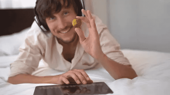 A Man Hold an NFT Coin in his Hand is a Stock Footage that shows a music DJ holds a golden NFT coin in his hand